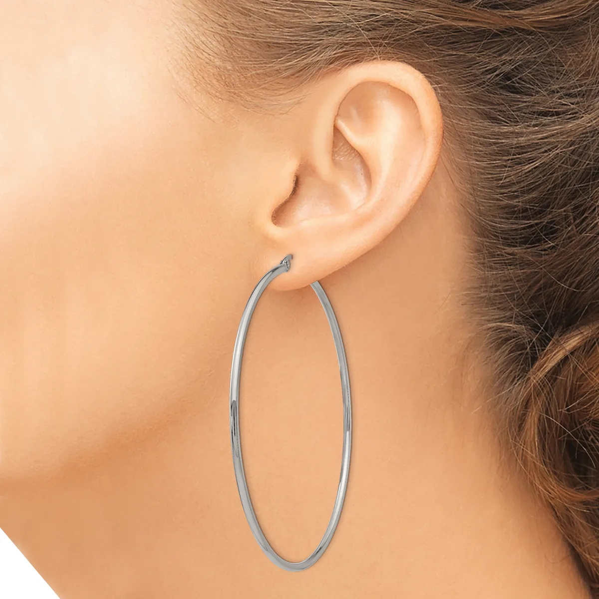 A person wearing a large oval hoop earring in silver-toned metal, shown from the side view of their ear and neck.