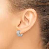A person wearing a brushed silver curved hoop earring in their earlobe, shown from the side view.