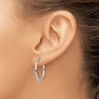 A woman wearing a polished silver hoop earring in her earlobe, shown in profile against her neck and shoulder.