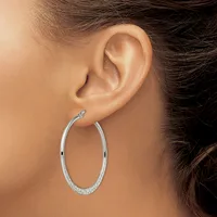 A person wearing a large oval silver hoop earring with a textured surface, shown from the side view of their ear and neck.