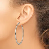 A woman wearing large oval hoop earrings with a textured surface, shown from the side profile of her face and ear.