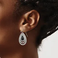 A person wearing a teardrop-shaped silver earring with a black stone center and textured concentric oval bands, shown from the side view of their ear.