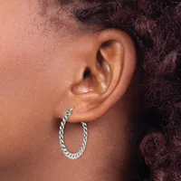 A person wearing a twisted silver hoop earring in their earlobe, shown in profile against their neck and shoulder.