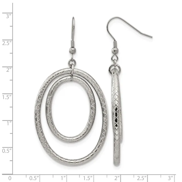 A pair of silver dangle earrings featuring textured oval loops on the left and textured cylindrical rods on the right, displayed against a measurement ruler.
