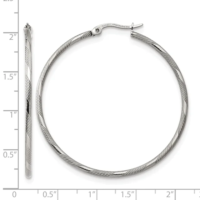 A pair of silver twisted hoop earrings with hinged closures, shown next to a ruler measuring approximately two inches in diameter.