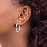 A person wearing silver textured hoop earrings with a hammered or dimpled surface finish, shown from the side profile against their ear.
