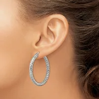 A person wearing textured silver hoop earrings with a hammered or dimpled surface finish, shown from the side profile of their ear.