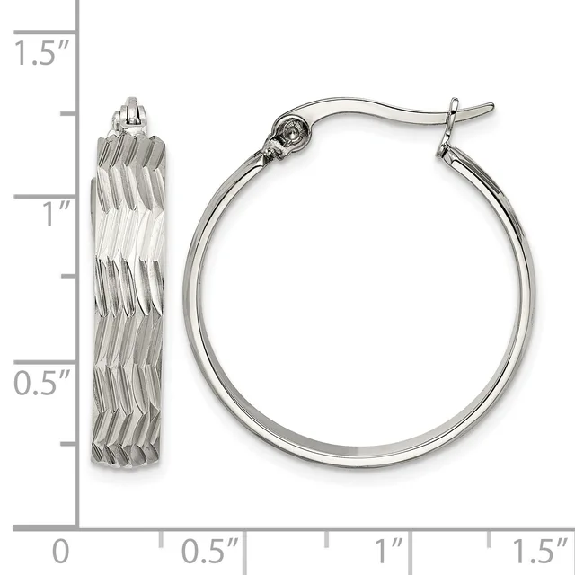 A pair of silver-toned hoop earrings with textured diagonal ridged surfaces, shown next to a measurement scale indicating approximately one inch in diameter.
