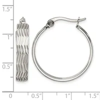 A pair of silver-toned hoop earrings with textured diagonal ridged surfaces, shown next to a measurement scale indicating approximately one inch in diameter.