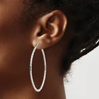 A person wearing a large oval silver hoop earring, shown from the side view of their ear and neck against a neutral background.