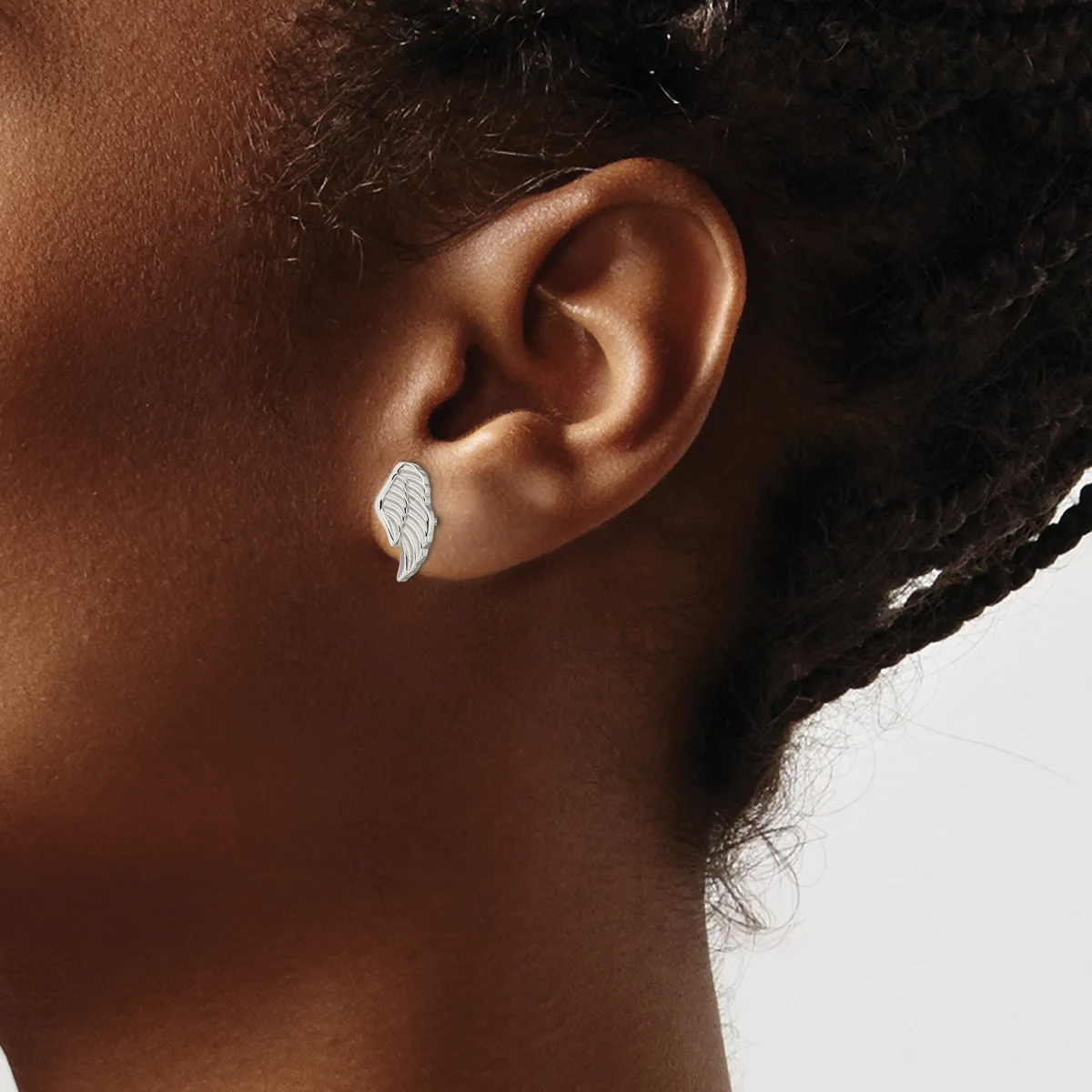 A person wearing a small silver leaf-shaped earring in their earlobe, shown in profile against a white background.