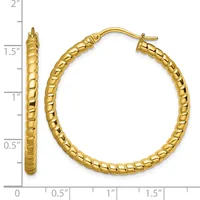 A pair of gold textured hoop earrings with a quilted surface pattern, shown against a measurement scale indicating approximately 1.5 inches in diameter.