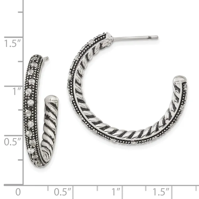 A pair of silver hoop earrings with twisted rope texture and beaded edges, displayed next to a measurement scale showing approximately one inch in diameter.