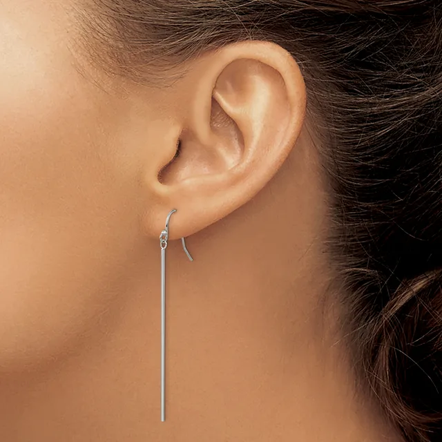 A person wearing a long silver threader earring that passes through the earlobe, with a small curved hook detail at the top.