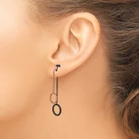 A person wearing dangling earrings with two circular rings connected by a delicate chain, shown from the side view of their ear.