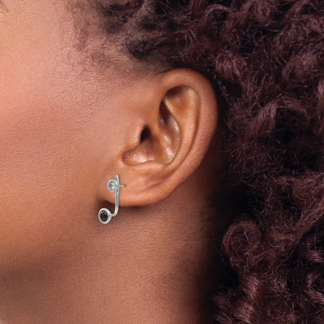 A person wearing a curved silver ear cuff with small circular blue stone details on both the upper and lower ends, displayed on their earlobe.