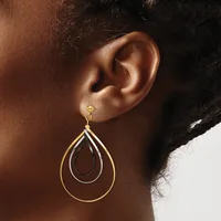 A person wearing a gold teardrop-shaped dangle earring with nested hollow teardrop outlines, shown from the side view near their ear.