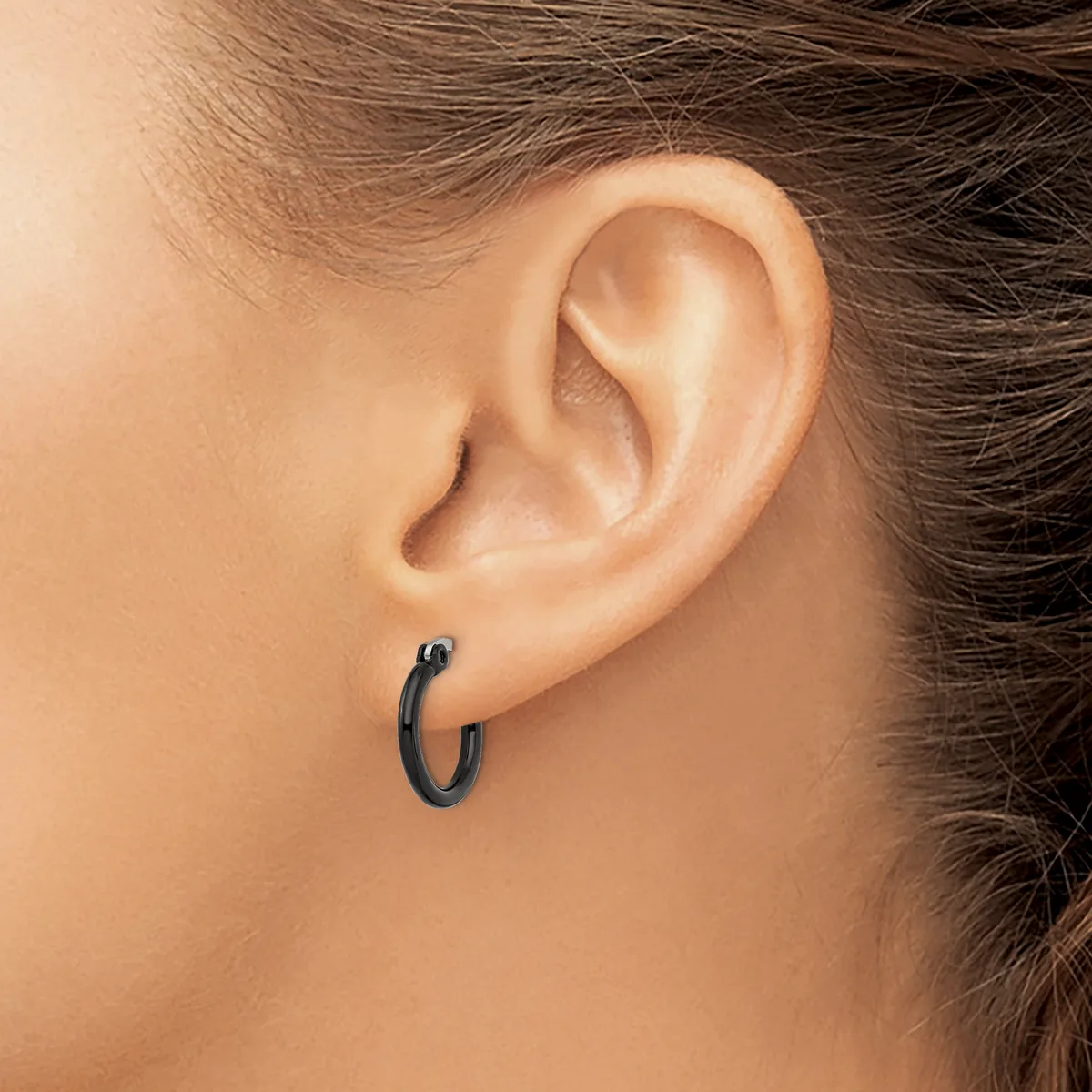 A person wearing small dark hoop earrings in their pierced earlobes, shown in profile view from the side of their head.