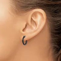 A person wearing small dark hoop earrings in their pierced earlobes, shown in profile view from the side of their head.