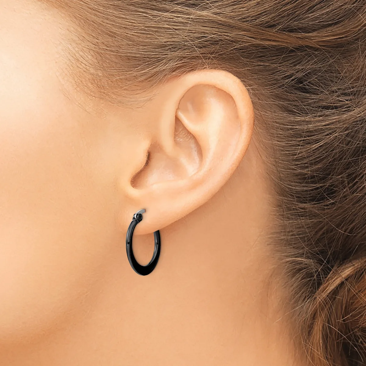 A person wearing a small black hoop earring in their earlobe, shown from the side profile view.