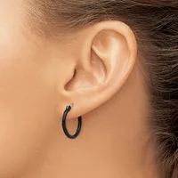 A close-up side view of a person's ear wearing a small black hoop earring.