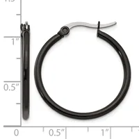 A pair of black hoop earrings with a polished finish and hinged closures, shown next to a ruler indicating they measure approximately one inch in diameter.