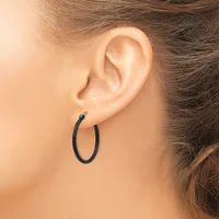 A person wearing a small black hoop earring in their earlobe, shown in profile against their neck and shoulder.