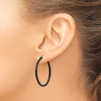 A person wearing a black oval hoop earring in their earlobe, shown in profile against their neck and shoulder.