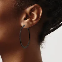 A person wearing a large oval hoop earring in dark metal, shown from the side profile against a neutral background.