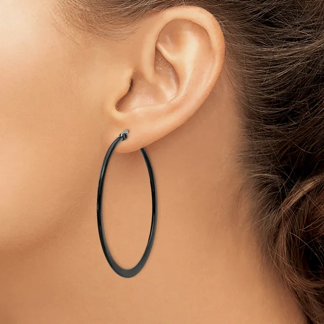 A person wearing a large black oval hoop earring visible from the side profile view of their ear and neck.
