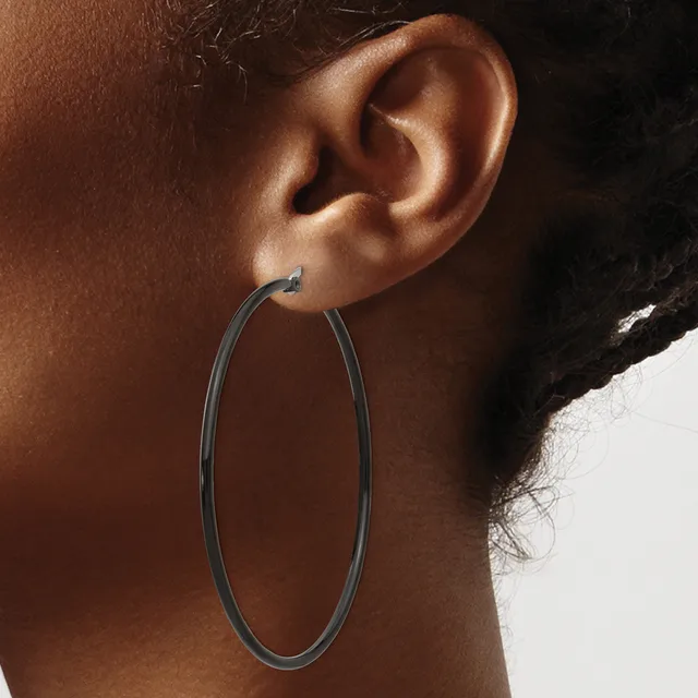 A person wearing a large oval hoop earring in dark metal, shown from the side profile against a neutral background.