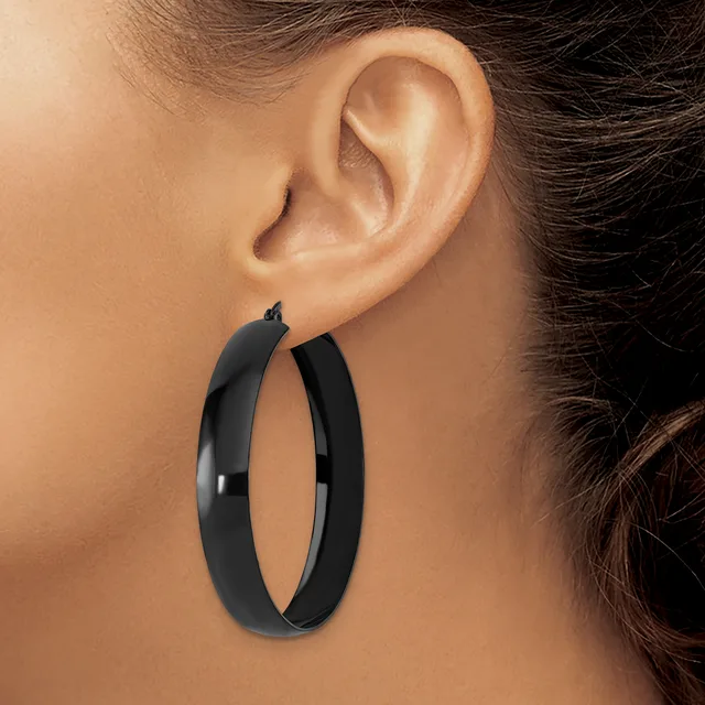 A person wearing large black hoop earrings with a polished finish, shown from the side profile view against their ear.