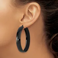 A person wearing large black hoop earrings with a polished finish, shown from the side profile view against their ear.