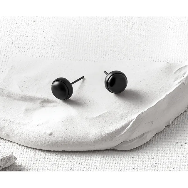 Two black spherical stud earrings with posts displayed on a white textured fabric surface.