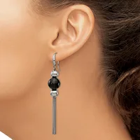 A woman wearing a dangling earring with a black sphere bead between two silver spheres and a long tassel chain hanging from a lever-back hook.