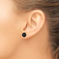 A person wearing a small black circular stud earring in their pierced earlobe, shown in profile view.