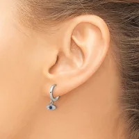 A person wearing a silver hoop earring with a small dangling pendant featuring a dark blue stone surrounded by smaller crystals.