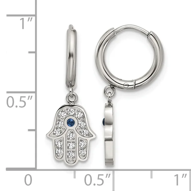 A pair of silver huggie hoop earrings with hamsa hand charms featuring white crystals and a blue stone center, shown next to a ruler for scale.