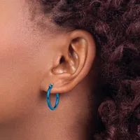 A person wearing a blue hoop earring in their earlobe, shown in profile with textured brown hair visible.