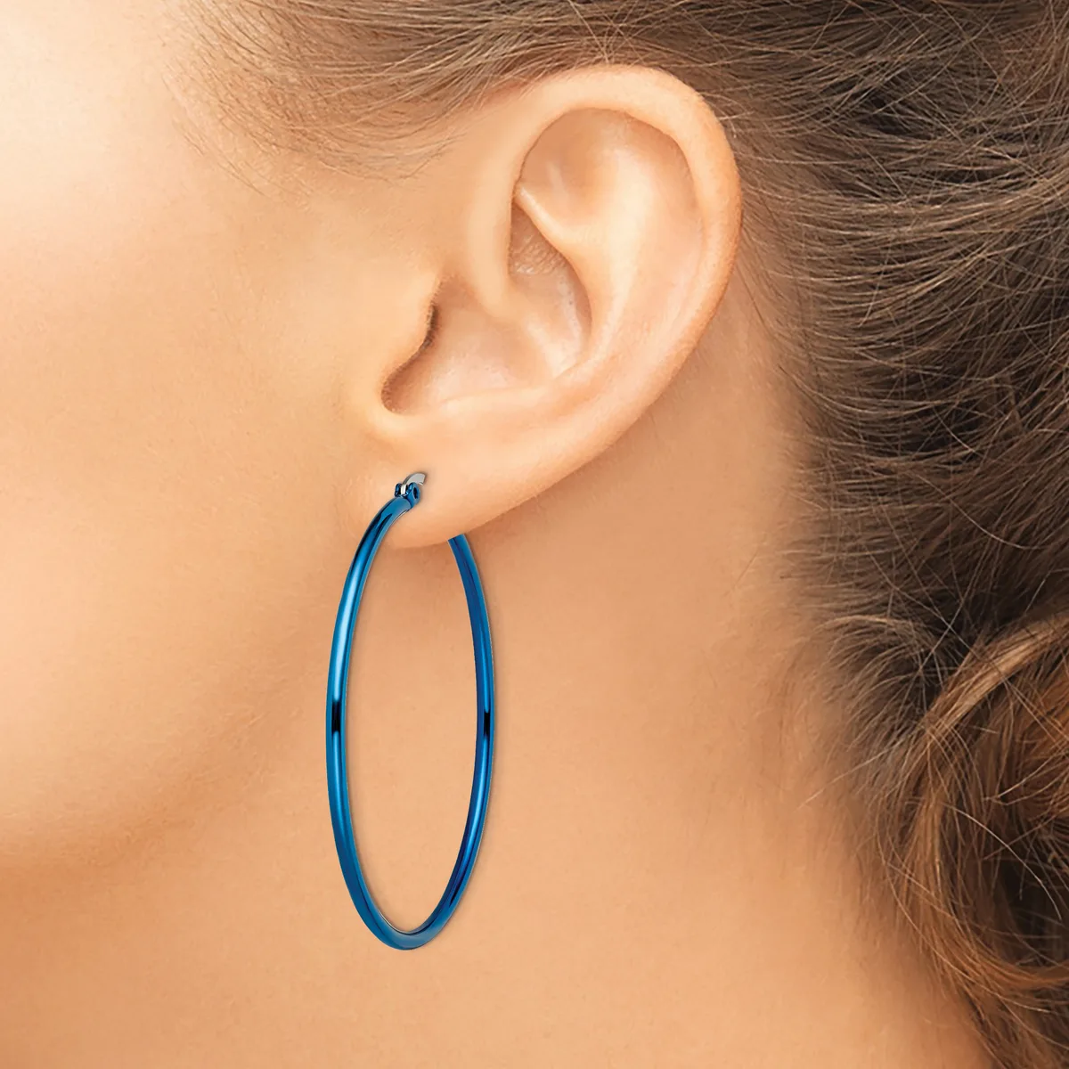 A person wearing a pair of blue hoop earrings, shown from the side profile of their ear and neck.