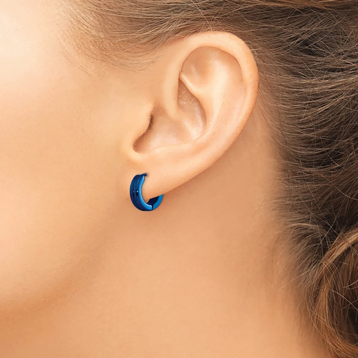 A person wearing a small blue curved hoop earring in their earlobe, shown in profile against bare skin.