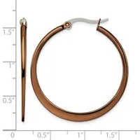 A pair of bronze-toned hoop earrings with surgical steel posts, displayed against a measurement scale showing they are approximately 1.5 inches in diameter.