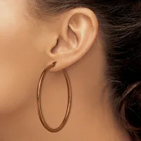 A person wearing a large oval bronze hoop earring in their earlobe, shown in profile against a neutral background.