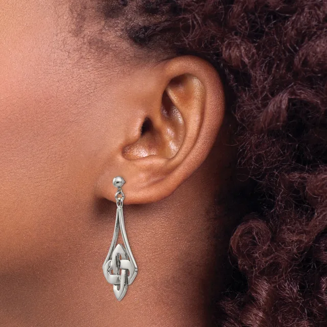 A silver teardrop-shaped dangle earring with a Celtic knot design, shown worn on a person's earlobe.
