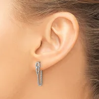 A silver chain hoop earring is worn in the pierced earlobe of a person with brown hair.