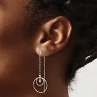 Silver threader earrings with concentric circular rings hanging from delicate chains, worn by a person shown in profile.