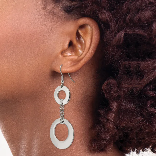 A person wearing a pair of dangling earrings made of white oval rings connected by a silver chain, shown from the side profile.