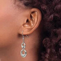 A person wearing a silver dangle earring with interlocking oval loops hanging from a curved hook, shown from the side against their ear.