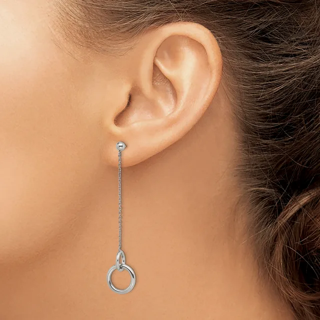 A person wearing a long silver chain threader earring with a small loop detail at the bottom, shown hanging from their earlobe.