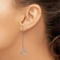 A person wearing a long silver chain threader earring with a small loop detail at the bottom, shown hanging from their earlobe.